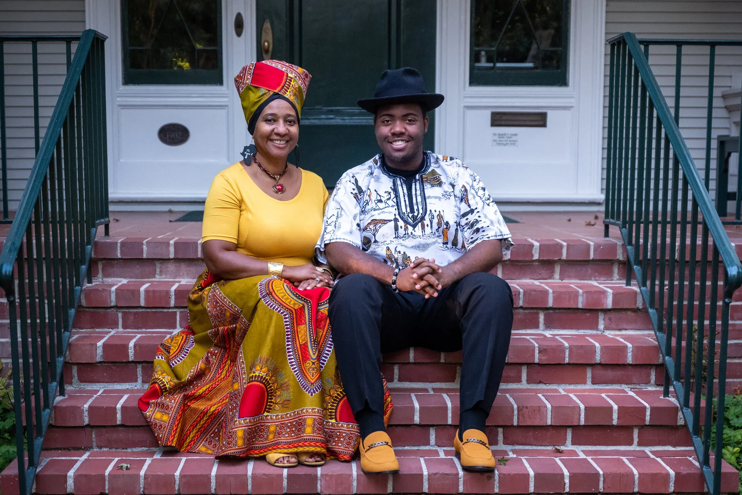 Thandiwe Jennifer Lyons and Balondemu Jules Lyons sitting on their front steps in colorful African attire