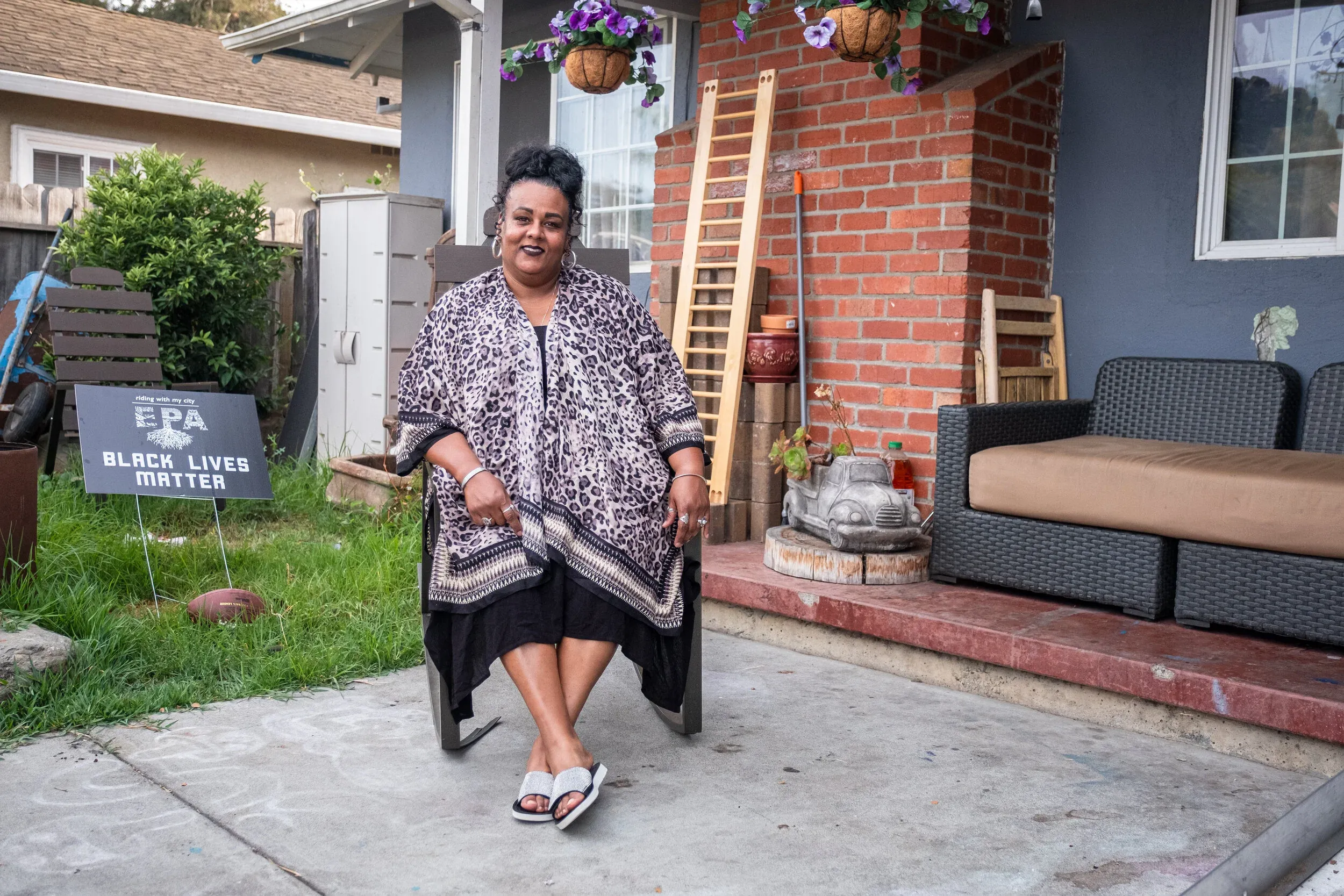 Lea Martinez sitting outside her East Palo Alto home with a Black Lives Matter sign in the yard