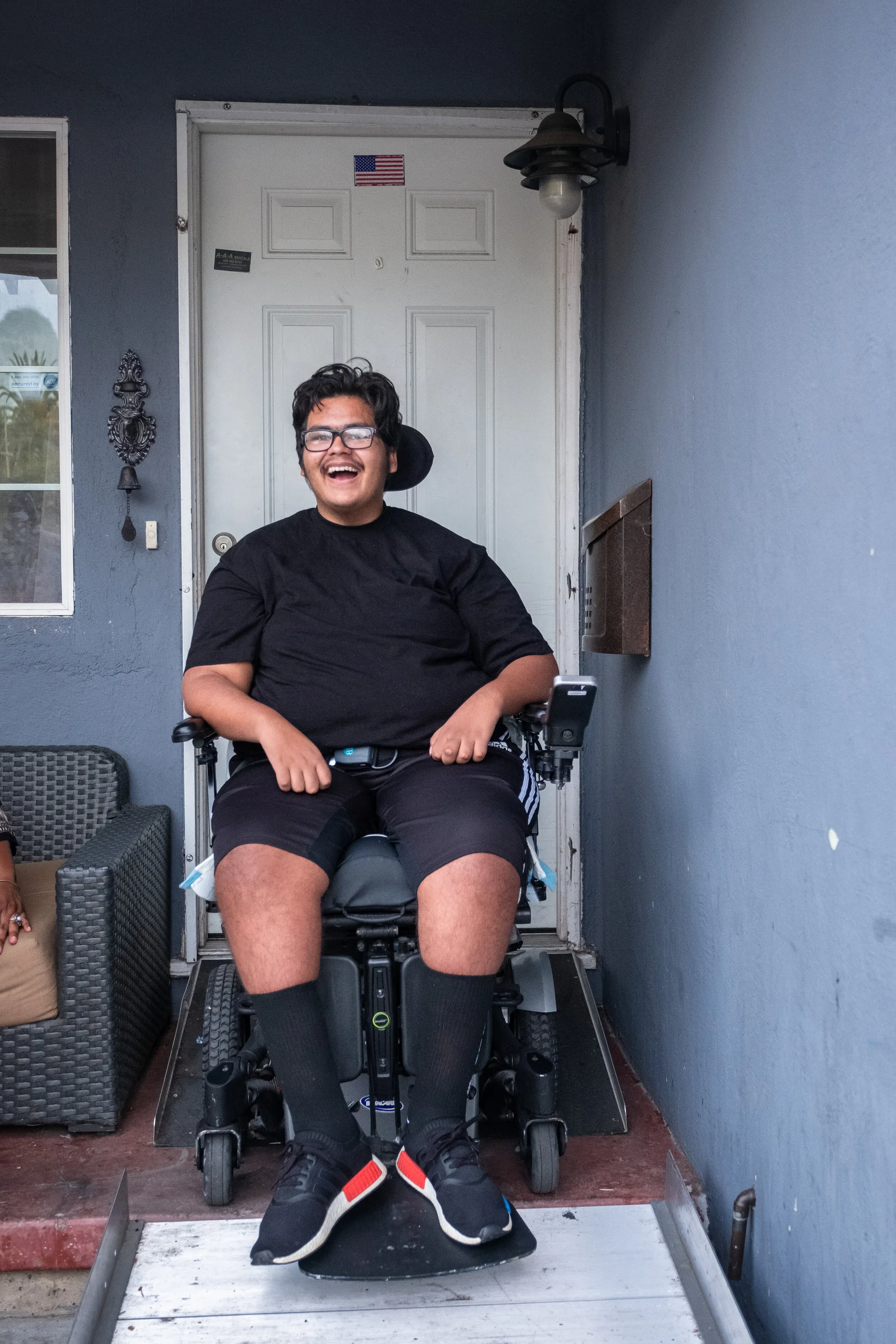 Austin, Lea's son, smiling in his wheelchair at the front door