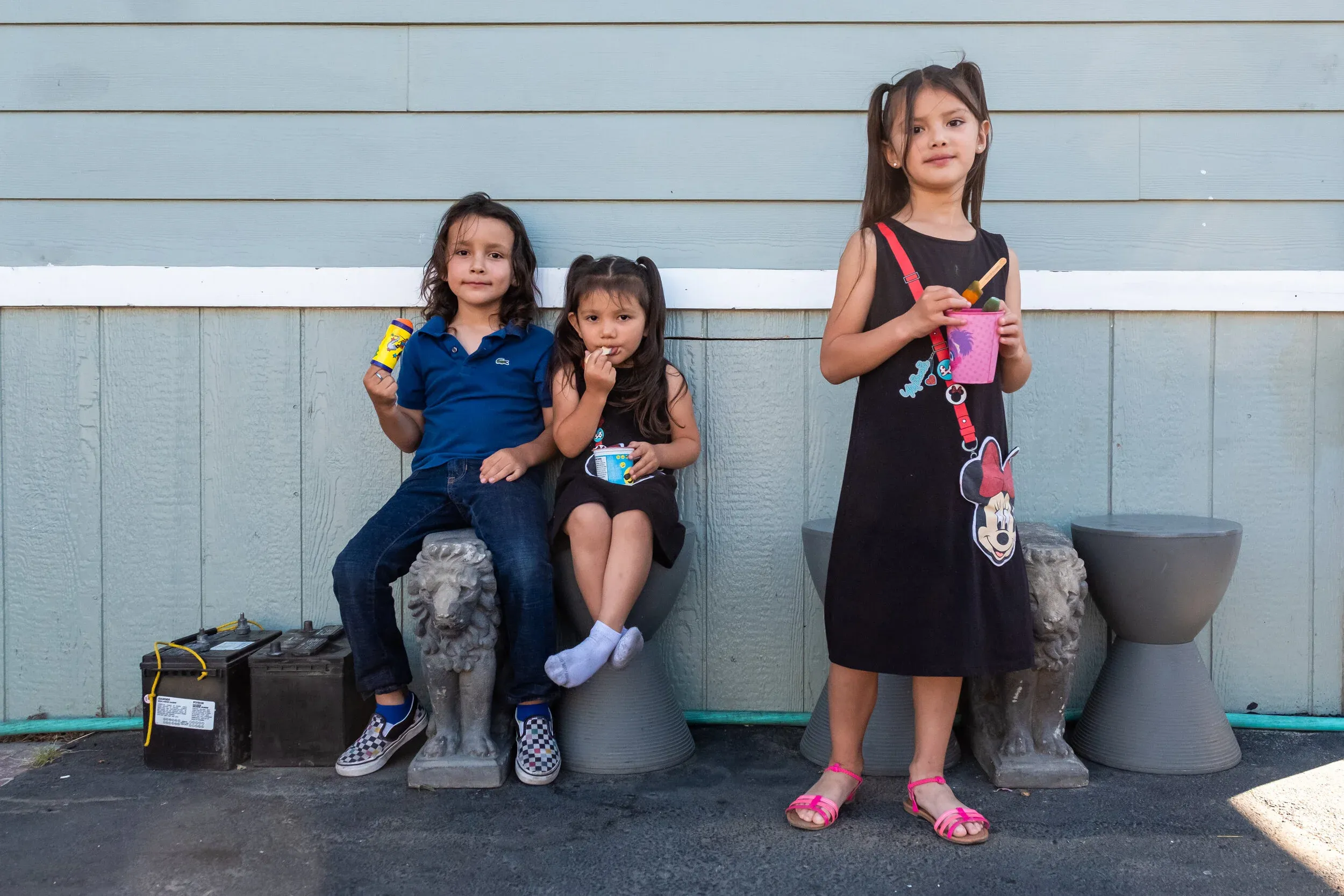 Angel, Sophie, and Sabrina — Shannon and Juan's three children — eating snacks outside their home