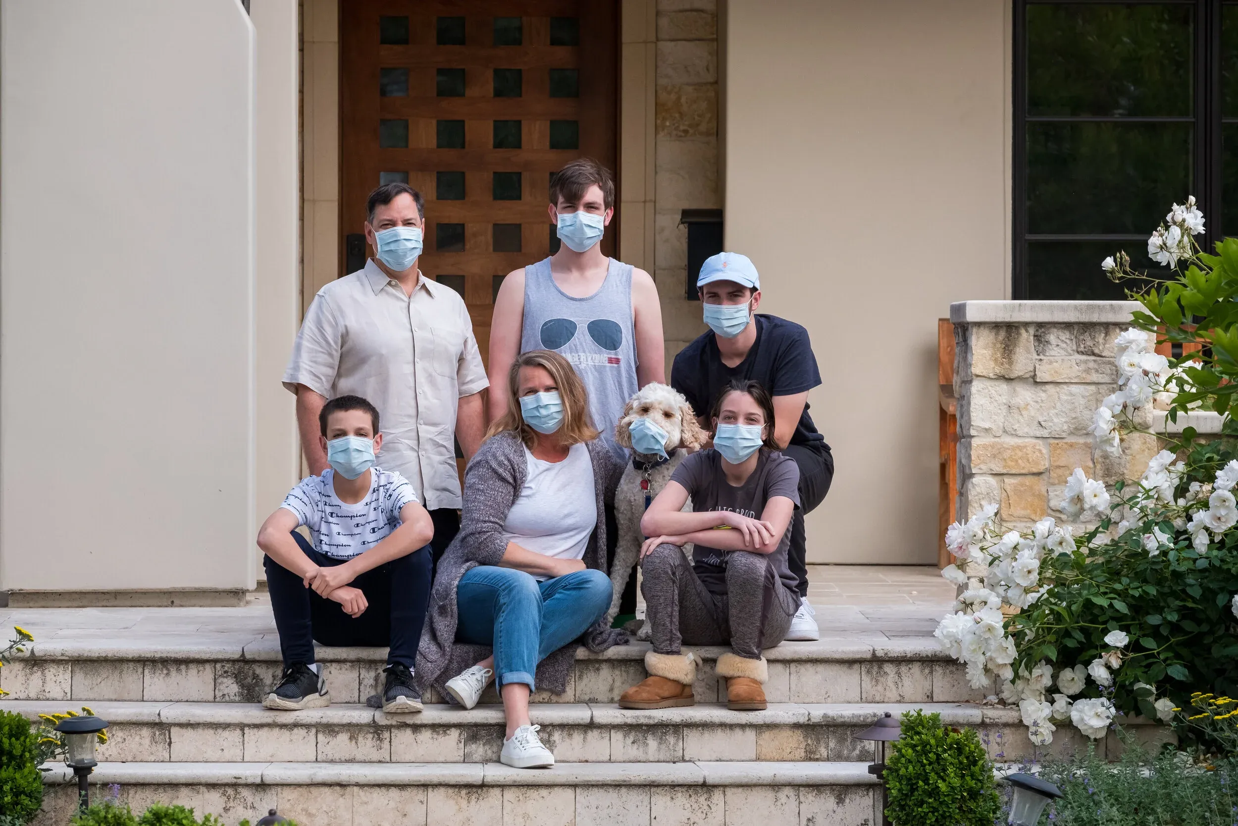 Family wearing masks with their dog on front steps